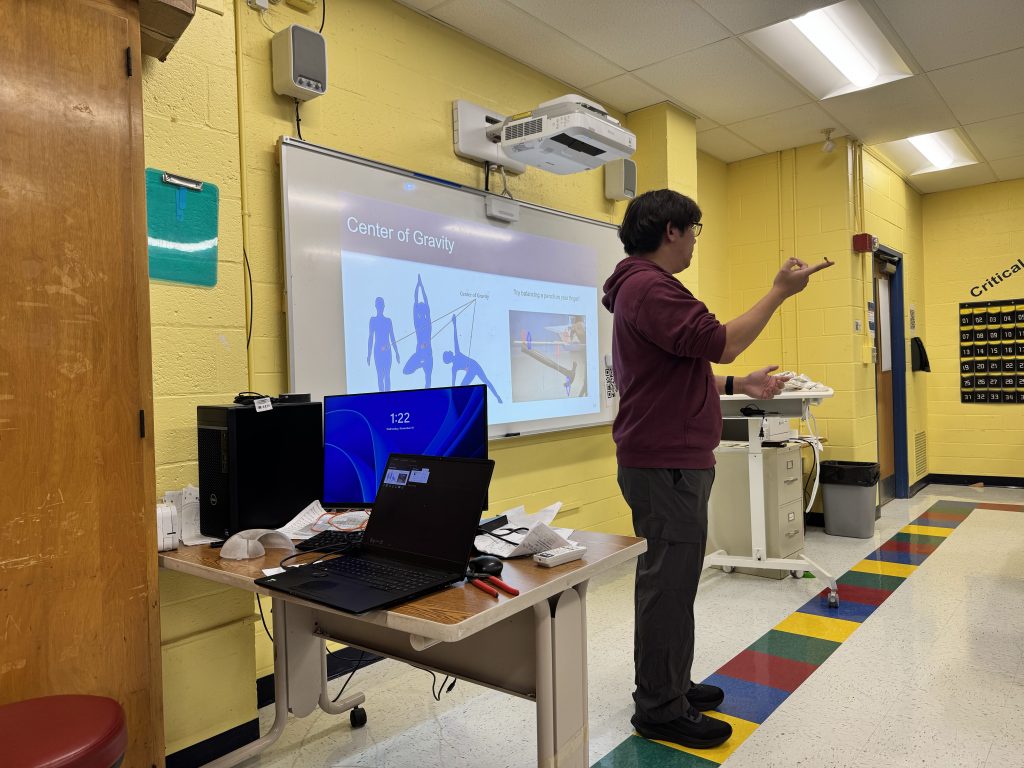 Alex Yin standing in front of a classroom giving a presentation to students.